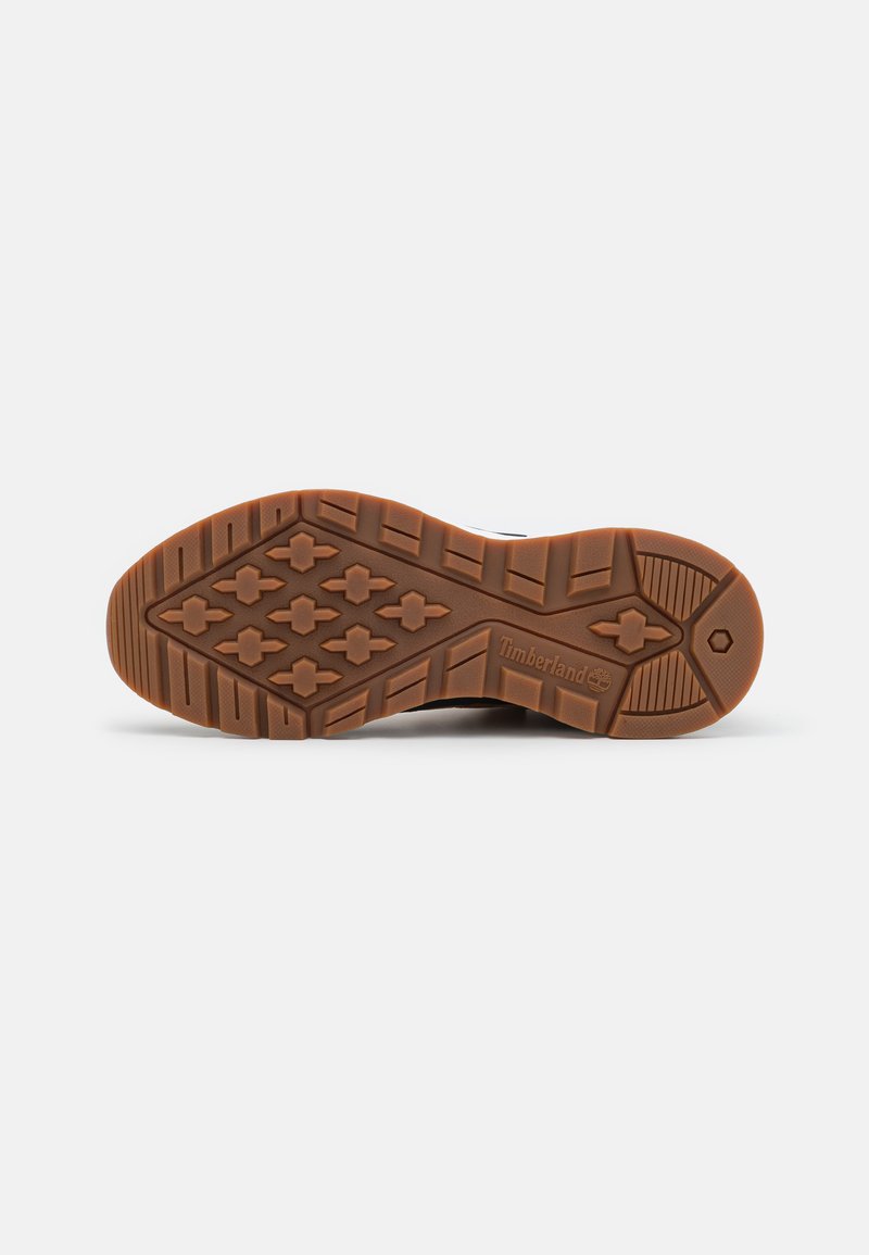 Brązowa gumowa podeszwa z bieżnikiem w geometryczne kształty i rowki, oznaczona logo "Timberland" z boku.