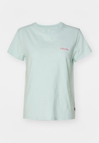 Vaaleansininen puuvillapaita, jossa on pyöreä pääntie, lyhyet hihat ja pieni vaaleanpunainen brodeerattu Levi's-logo vasemmalla puolella.