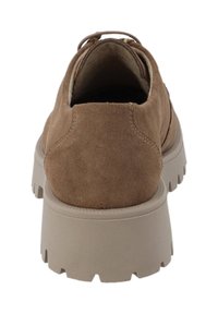 Zapato de ante marrón con una suela de goma gruesa beige, punta redondeada y parte superior suave. Cuenta con una asa en la parte trasera para facilitar su puesta.