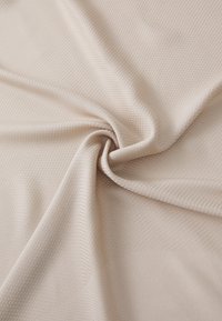 Lys beige teksturert stoff med et subtilt geometrisk mønster, som viser myke fall og en glatt overflate. Ideell for allsidige tekstilapplikasjoner.