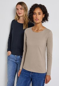 Långärmade toppar i mörk marinblå och ljus beige, med rund halsringning och mjuka, släta texturer, i kombination med denimjeans.