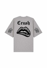 T-shirt gris à manches courtes avec texte gothique noir "Crush" au-dessus d’un grand graphisme de lèvres et de motifs de cœur en flammes sur les deux manches.