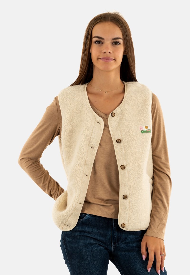Gilet in pile di colore crema, con bottoni frontali, collo rotondo e dettagli a toppa. Abbinato a una maglietta a maniche lunghe beige.