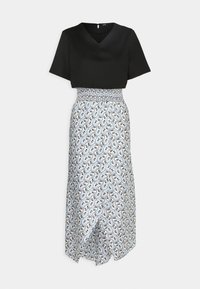 Haut court noir associé à une jupe taille haute longueur cheville, avec imprimé floral cachemire bleu et blanc et taille smockée.