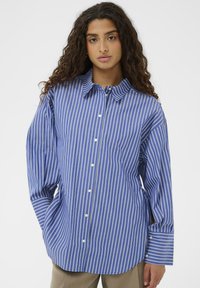 Blå stribet skjorte med knaplukning og lange ærmer, der har hvide lodrette striber og en klassisk krave. Fremstillet af letvægtsstof.