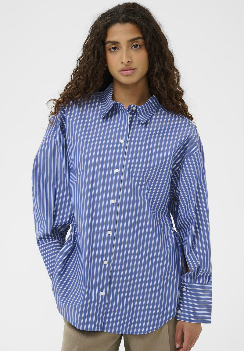 Blå stribet skjorte med knaplukning og lange ærmer, der har hvide lodrette striber og en klassisk krave. Fremstillet af letvægtsstof.