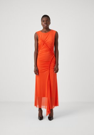 Orange sleeveless dress with diagonal ruching, textured fabric, floor-length sheer overlay, and high slit, paired with black heeled shoes.