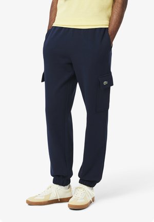 Pantalones cargo azul marino hechos de una tela suave, con puños elásticos, bolsillos laterales y un pequeño detalle de logo en el bolsillo cargo.