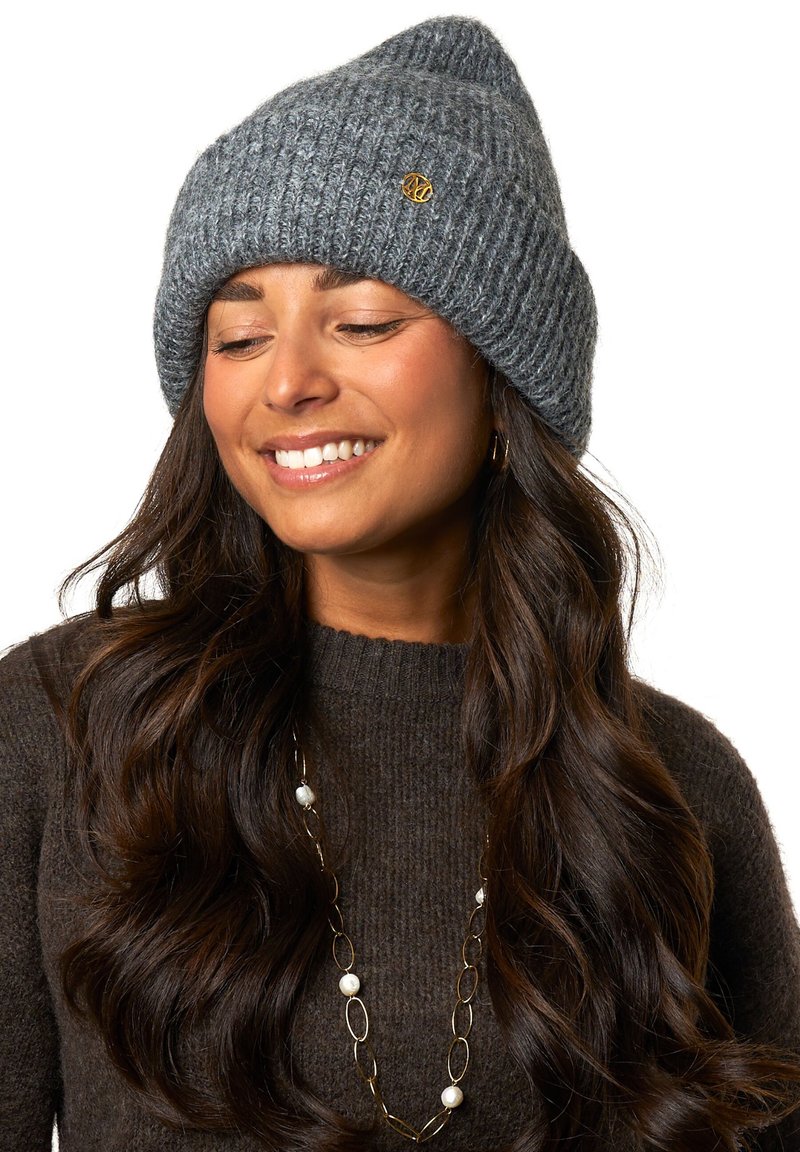 Grijze gebreide beanie met een omgeslagen ontwerp en een klein gouden logoaccent. De stof lijkt zacht en textuur te hebben, geschikt voor koudere weersomstandigheden.