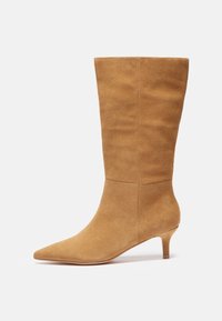 Bottes à cheville en daim marron avec un bout pointu et un petit talon, présentant une texture lisse et un design simple sans accents supplémentaires.