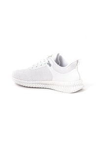 White athletic shoes with a knit upper, textured surface, and rubber sole featuring a distinctive geometric pattern.