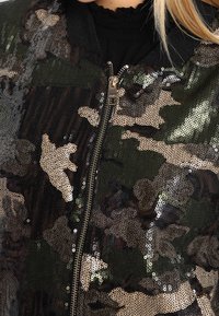 Camo bomberjack met een paillettendesign in tinten zwart, groen en beige, voorzien van een ritssluiting aan de voorkant en een geribde kraag.