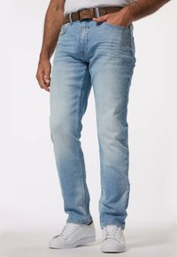 Jeans de denim azul claro con un corte recto, que presentan un ligero desvanecimiento y detalles desgastados. Combinados con un cinturón marrón y zapatillas blancas.