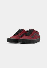 Sneakers in suede rosso con suola in gomma nera, caratterizzati da lacci neri e una striscia laterale nera. Design a profilo basso con suola testurizzata.