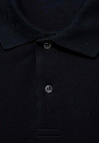 Námořnická polokošile s texturovanou tkaninou, vybavená dvoubarevnou légou a klasickým límcem. Obsahuje šité švy a jemné detaily.