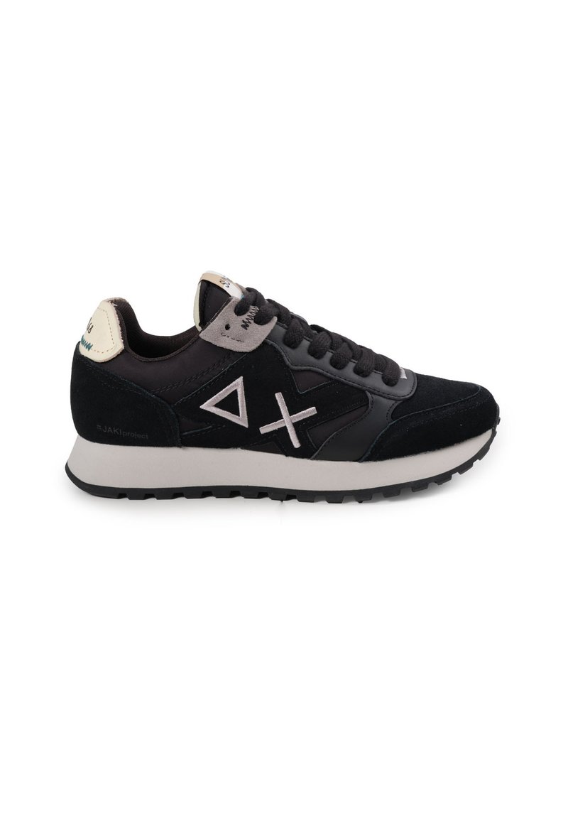 Sneaker nera e grigia con tomaia in suede, motivi triangolari e incrociati, lacci piatti e suola in gomma texturizzata. Tab in crema sul tallone.