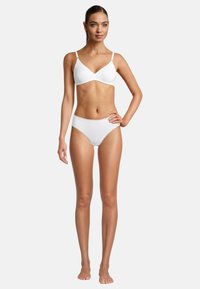 Weißer kabelloser BH kombiniert mit passendem weißen Slip. Glatter Stoff, einfaches Design und zarte Spitzenverzierung am Slip. Elegant und minimalistisch.
