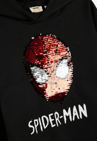 Svart hoodie med en sequin Spider-Man ansiktsdesign i rött, vitt och silver, med texten "SPIDER-MAN" nedanför.