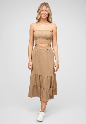 Ensemble deux pièces marron composé d'un haut smocké sans bretelles et d'une jupe maxi à volants, fabriqué en tissu léger. Associé à des baskets blanches.