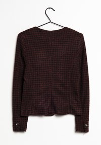 Pitkähiha, teksturoitu takki tummanpunaisessa ja mustassa ruudullisessa kuosissa. Pyöreä kaula-aukko ja napitettu hihansuu. Ripustettuna mustasta metallikoukusta.