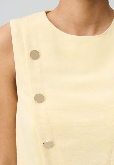 Top senza maniche di colore giallo chiaro con scollatura tonda, caratterizzato da tre bottoni argentati sul lato sinistro e una finitura in tessuto testurizzato.