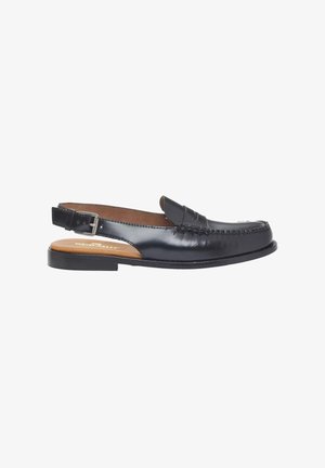 Mocasín slingback de cuero negro con correa de hebilla, costura en la puntera estilo mocasín y suela plana, exhibido sobre fondo blanco.