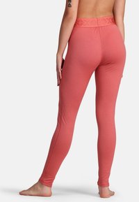 Roze leggings met een gestructureerde tailleband, een slimfit ontwerp en gladde stof, getoond van achteren met blote voeten zichtbaar.