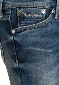 Vaqueros azules de mezclilla con corte ajustado, bolsillo delantero con el bordado del logo "Pepe Jeans" y detalles de herrajes en tono plateado.