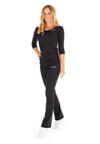 Schwarzes langärmeliges Sportoberteil mit pinkfarbenen Akzenten und Logo. Enganliegende schwarze Hosen aus dehnbaren Stoff mit weißen Sneakers für sportliche Aktivitäten.