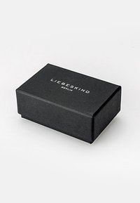 Zwarte rechthoekige doos met een textuur en het reliëf witte logo "LIEBESKIND BERLIN" op het deksel.