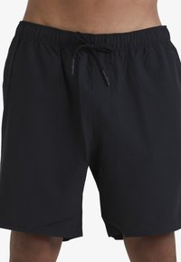 Shorts de bain noirs en matériau léger, dotés d'une taille élastique et d'un cordon de serrage ajustable. Présente un détail de couture à l'avant.