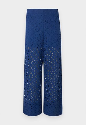 Modré kalhoty s širokými nohavicemi s propracovanými květinovými vzory vyřezávanými laserem a béžovou podšívkou pod nimi.