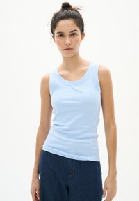 Hele helesinine ribaga tank top ümmarguse kaelusega ja ohne varrukatega, koos tumedate teksadega. Siluett on korralik ja tekstuur on sile.