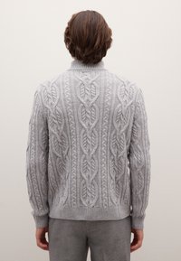 Suéter de punto trenzado gris con patrones intrincados y un cuello alto, hecho de un material suave y texturizado. Puños y dobladillo de canalé.