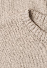 Beżowy sweter dziany z prążkowanym okrągłym kołnierzem, ukazujący szczegółową teksturę włóczki i wzór dzianiny.