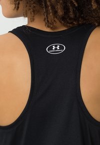Top nero senza maniche realizzato in un tessuto morbido, con design a schiena scoperta. Logo Under Armour bianco sulla parte superiore della schiena.