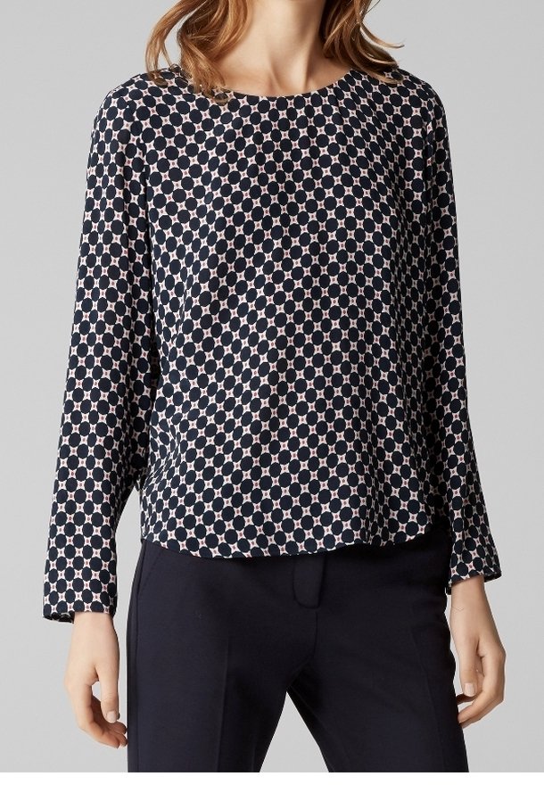 Blusa navy con motivo circolare rosa, scollo rotondo e maniche lunghe. Tessuto leggero, vestibilità rilassata, abbinata a pantaloni scuri.