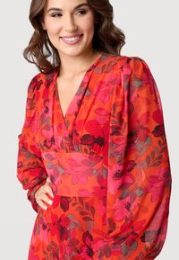 Rode jurk met een V-hals en lange pofmouwen, met florale patronen in roze, rood en grijs. Lichtgewicht stof met een gladde textuur.