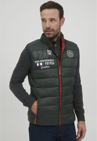 Dunkelgrüwest Pufferweste mit hohem Kragen, roten Reißverschlussakzenten und bestickten Grafiken, einschließlich "924" und "Quebec." Hat seitliche Taschen.