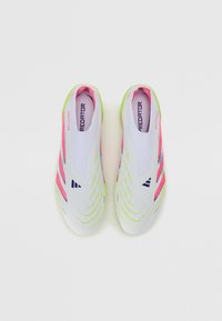 Lace-less athletic shoes with a white body, pink and neon green accents, textured lines, and a flat sole. "Predator" logo visible inside.