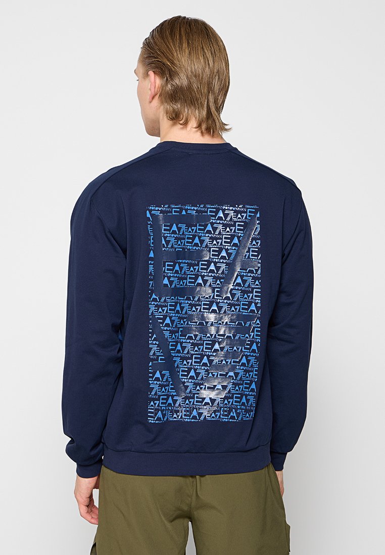 Sudadera azul marino con un gran diseño gráfico azul en la parte posterior, que presenta texto repetido y formas geométricas. Puños y dobladillo acanalados.