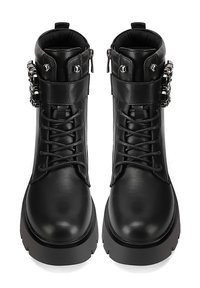 Stivali alla caviglia in pelle nera con laccio frontale, suola spessa e hardware decorativo sul lato. Texture liscia e design robusto.