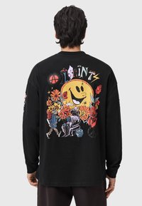 Camiseta negra de manga larga con un diseño gráfico colorido en la parte trasera, que muestra flores, un sol sonriente y personajes de dibujos animados.