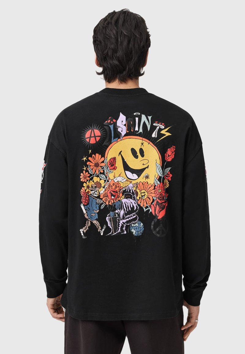 Camiseta negra de manga larga con un diseño gráfico colorido en la parte trasera, que muestra flores, un sol sonriente y personajes de dibujos animados.