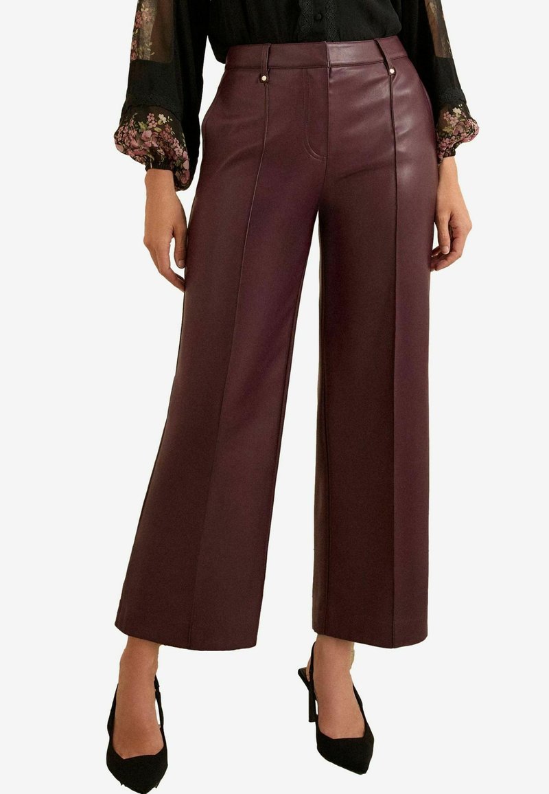 Burgunderfarbene Fake-Leder-Hosen mit weitem Bein, versehen mit genähten Vorderteilen und goldenen Knopfdetails, kombiniert mit schwarzen High Heels.