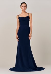 Temno modra oprijeta večerna obleka s tankimi naramnicami, nabranim izrezom in razširjeno krilom, ki se razteza v vlečko. Gladek tekstura in elegantna zasnova.