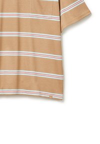 Krátký rukáv tričko v tan barvě se vodorovnými pruhy světle modré a červené. Obsahuje kapsu na hrudi a je vyrobeno z měkké bavlny.