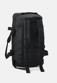 Sac à dos noir en matériau durable et texturé. Il possède des bretelles réglables, des boucles latérales, et un grand compartiment zippé sur le dessus.