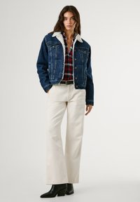 Denim takki, jossa on sherpa-kaulus, sininen väri, nappikiinnitys, kaksi rintataskua. Yhdistetty ruudullisen flanellipaidan, valkoisten housujen ja mustien korkokengien kanssa.