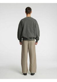 Pelēka lielizmēra džempera jaka ar ribotu apkakli, atbilstošiem manžetēm un apakšu. Bēša platu kāju bikses ar gludu tekstūru un smalku spīdumu.